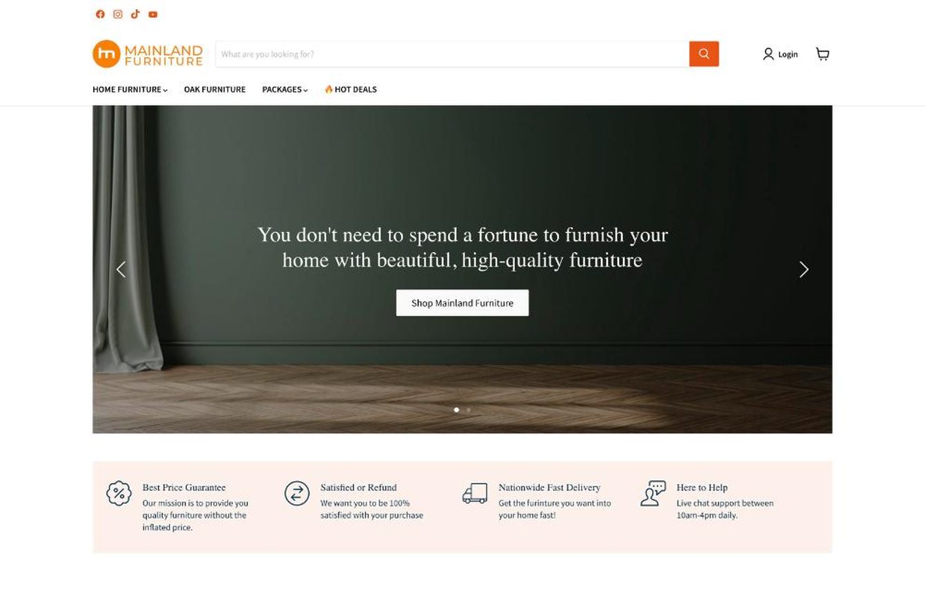 Mainland Furniture homepage in February 2023: the new orange logo, a search bar and a dark green banner.