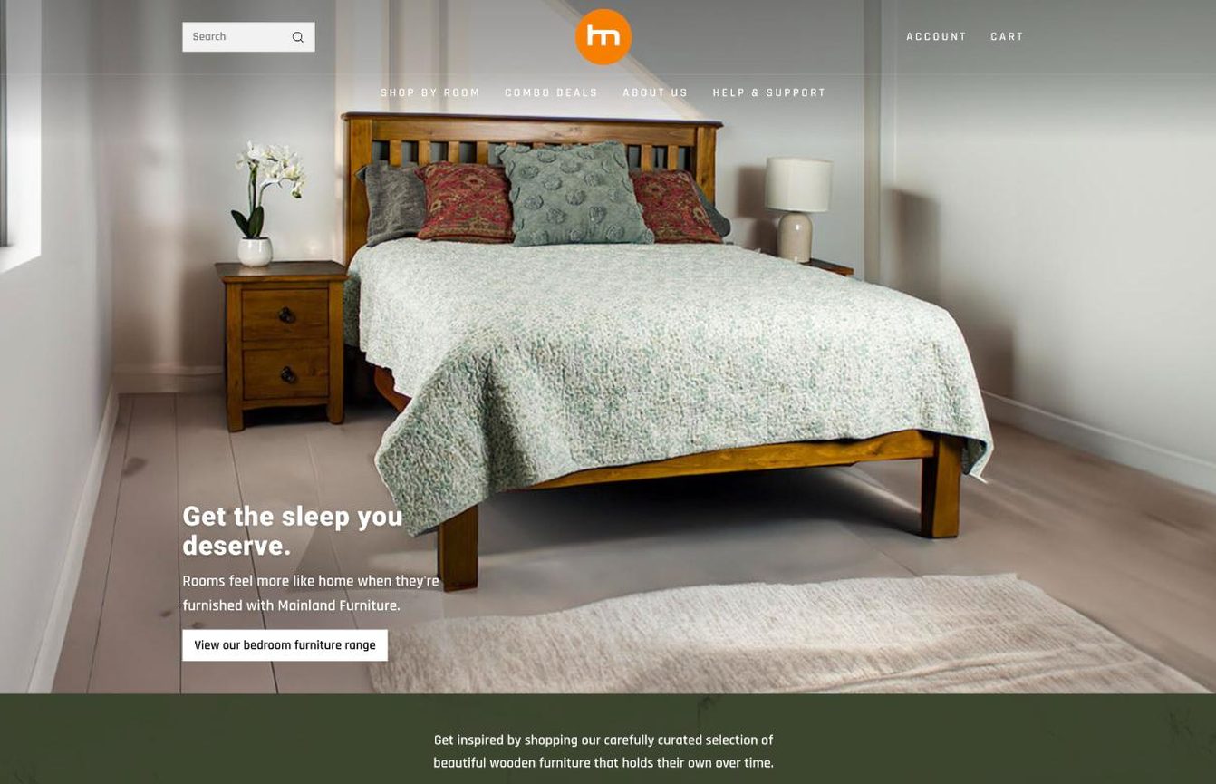 Mainland Furniture homepage in June 2024: a full-width photo of a wooden bed with the circular logo above it.