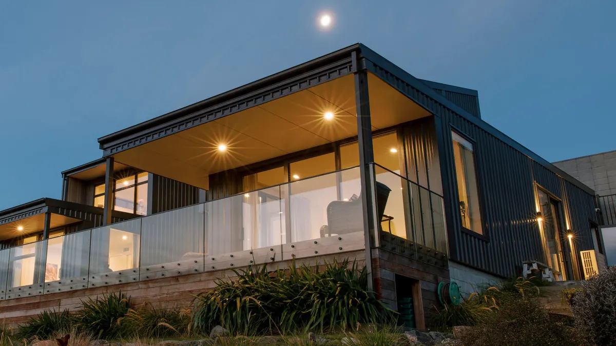 An architectural home by R&B Build, lit up at dusk.